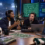Three soccer podcast hosts discuss tactics in a modern studio with microphones, screens, and a ball.